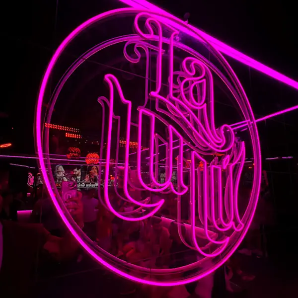 Logotipo de Lulú Show Bar iluminado en neón rosa.