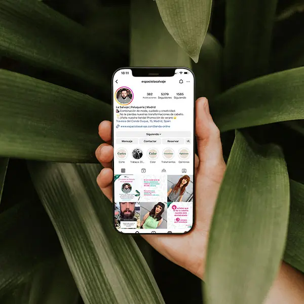 Perfil de Instagram de La Salvaje, peluquería en Madrid, mostrado en un teléfono móvil sobre un fondo de hojas.